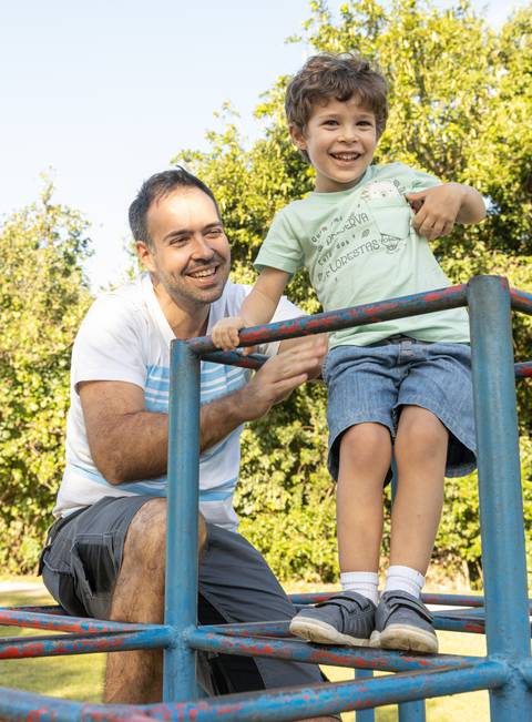 Fotografia de família com pai e filho no brinquedo de praça'
