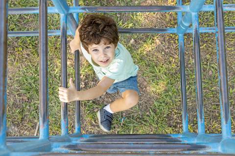 Fotografia de família com menino no brinquedo de praça'