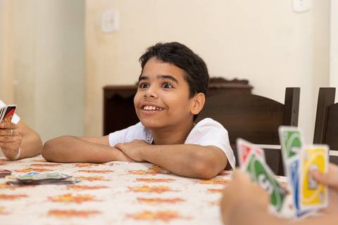 Fotografia de família com menino sorrindo à mesa'