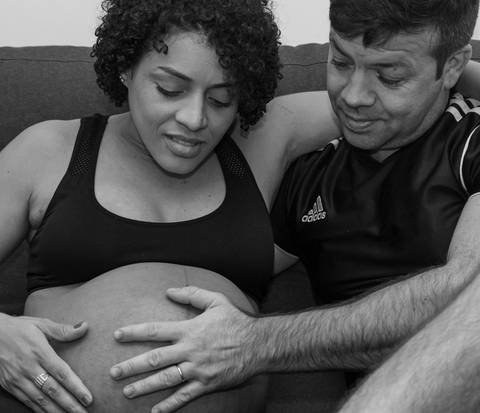Fotografia de família com casal acariciando a barriga da gestante'