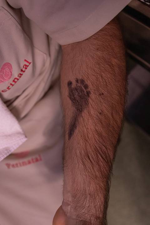 Fotografia de família com pezinho do bebê carimbado no braço do pai'