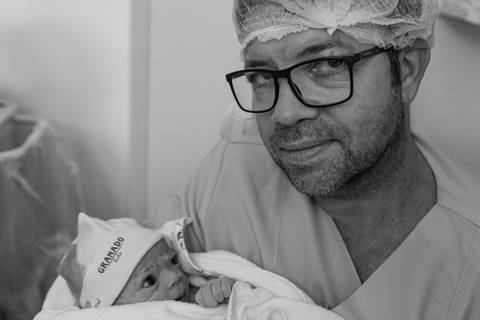 Fotografia de família com pai e bebê na sala de parto'