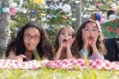 Fotografia de família com crianças deitadas sobre toalha de piquenique'
