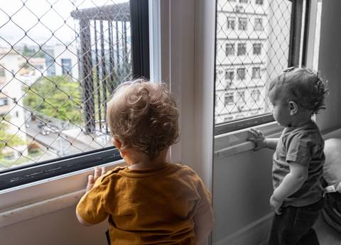 criança olhando pela janela'