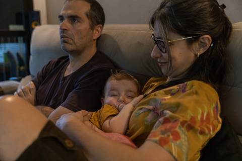 pais no sofá com filha dormindo nos braços'