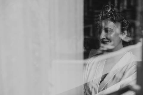 noiva rindo enquanto é fotografada pelo lado de fora da janela'