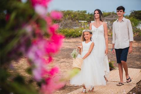filha mais noiva entrando jogando flores ao lado de seus dois irmãos'