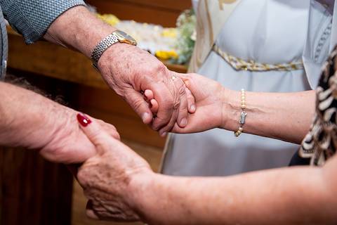 casal segurando a mão um do outro aliança  bodas de ouro'
