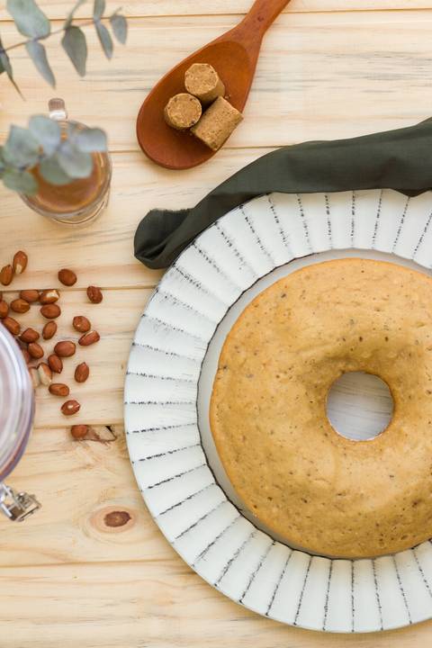 bolo de paçoca sobre uma mesa com alguns grãos de amendoim e uma calda de paçoca'