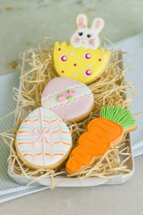 biscoitos decorados com o tema de pascoa sobre palha. Biscoito em forma de ovo de páscoa, cenoura, coelhinho da pascoa.'