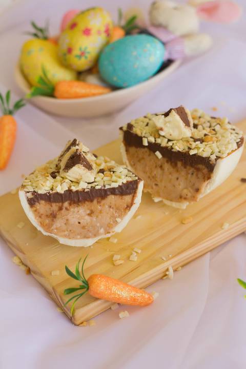 ovo de páscoa artesanal de colher feito em chocolate branco partido ao meio sobre uma pequena tábua de madeira onde vemos o recheio no interior'