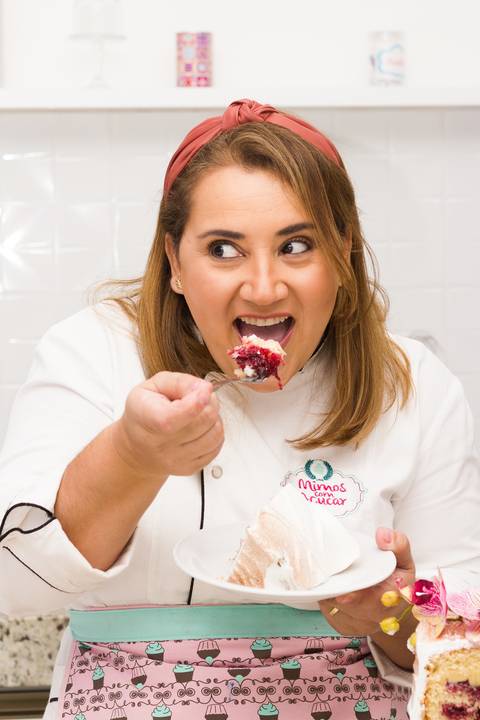 chef confeiteira comendo uma fatia de bolo de forma descontraída'