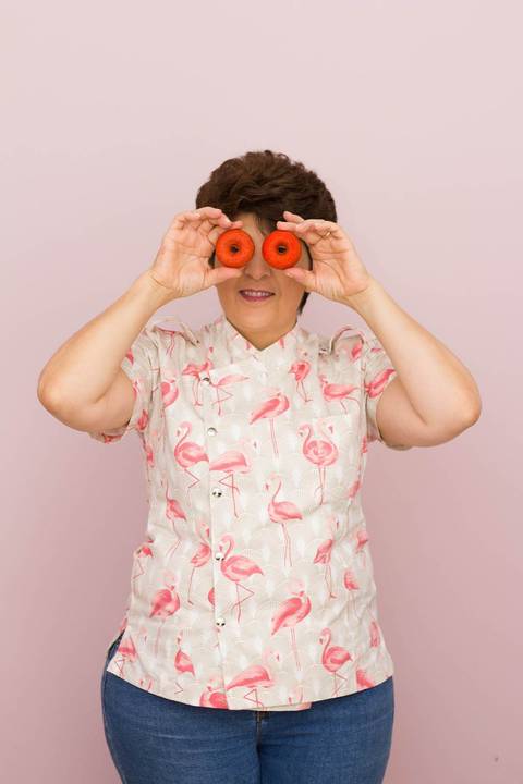 chef confeiteira posa para foto divertida em um fundo rosa  de maneira descontraída'