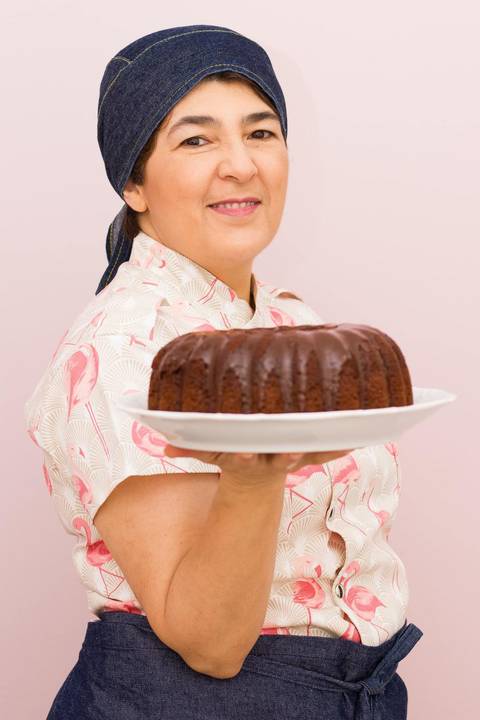 Confeiteira Regina Meynard segurando um bolo caseiro de chocolate com cobertura de chocolate '