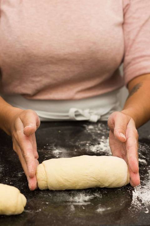pão de batata sendo modelado sobre uma bancada de mármore coberta de farinha'