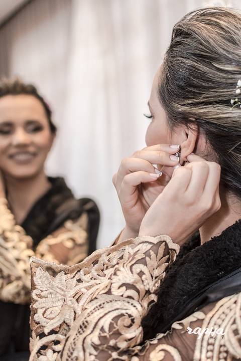 Fotografia tirada pelo fotógrafo de casamentos em BH, da noiva se preparando com colocando o brinco para o casamento.'