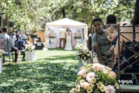 Foto com foco em criança convidada, com casamento ocorrendo em desfoque ao fundo da fotografia. Momento registrado pelo fotógrafo de casamentos em BH Rapha Drummond'