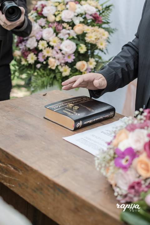 Rapha Drummond, que é fotógrafo de casamentos em Belo Horizonte, registra o momento em que o pastor está com sua mão direita sobre a bíblia.'