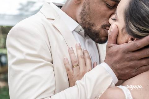 Fotografia de Casamento, por Rapha Drummond de BH, registra momento do beijo do casal em ângulo lateral.'