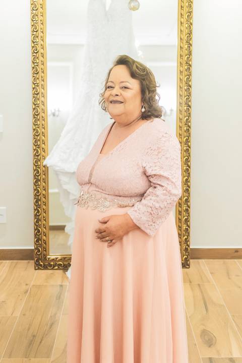 Fotografia antes do casamento no dia da noiva, da mãe da noiva, com o vestido ao fundo.'