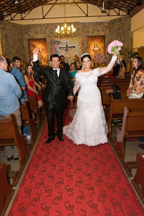 Saída festiva dos noivos Flávia e Maurício sob chuva de arroz e sorrisos reais - Fotografia de casamento BH'