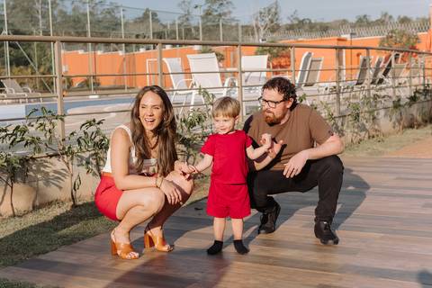 Família sentada no chão interagindo com o Léo em momento espontâneo da festa'