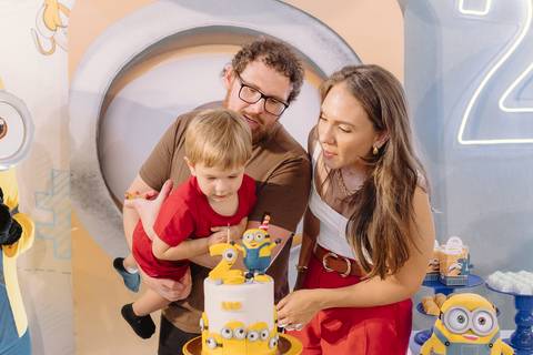 Família reunida ao redor do bolo temático dos Minions durante os parabéns'
