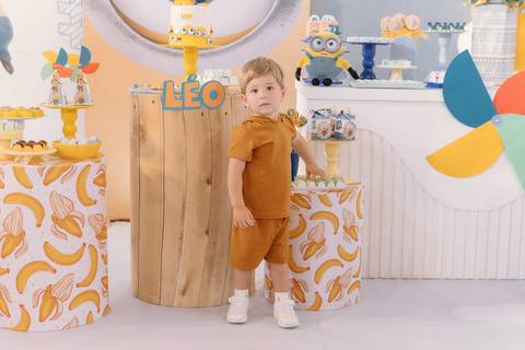 Léo em frente à mesa decorada com tema Minions no aniversário de 2 anos'
