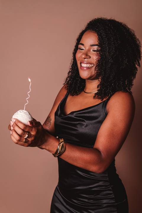 foto de uma mulher posicionada de lado, se sentindo linda com a velinha em cima do cupcake  comemorando seu aniversário'