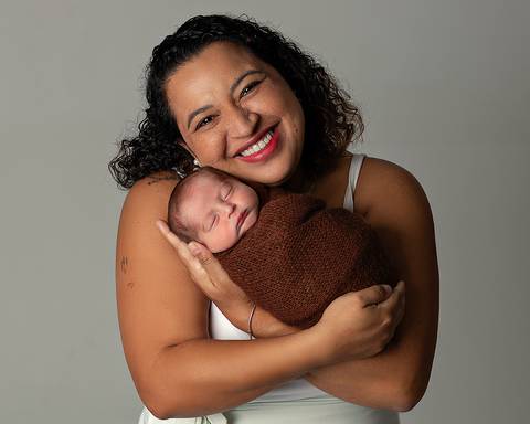Ensaio Newborn de mãe e bebê. Bebê enrolado em tecido, formando casulinho.'