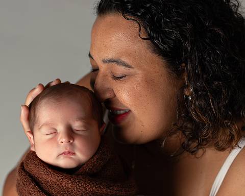 Ensaio Newborn de mãe e bebê. Bebê enrolado em tecido, formando casulinho.'