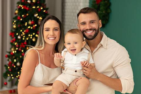 Mãe e pai com bebê em ensaio de Natal no Estúdio Amoradia Foto.'