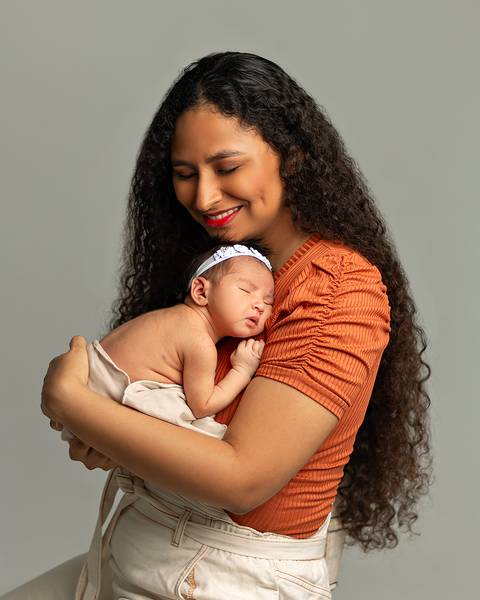 Bebê recém-nascida nos braços da mãe em ensaio Newborn'