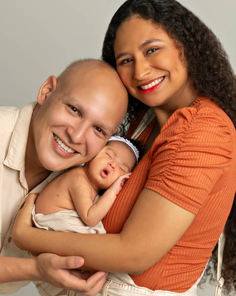 Ensaio de recém nascido em estúdio. Bebê nos braços da mãe e do pai. '