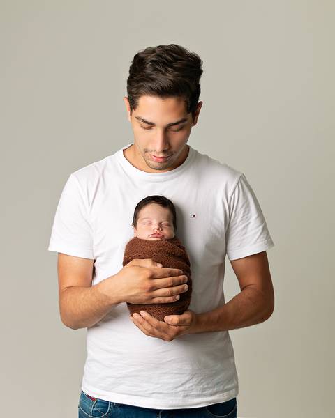 Bebê recém-nascido em ensaio Newborn com o pai.'