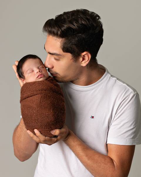 Bebê recém-nascido em ensaio Newborn com o pai.'