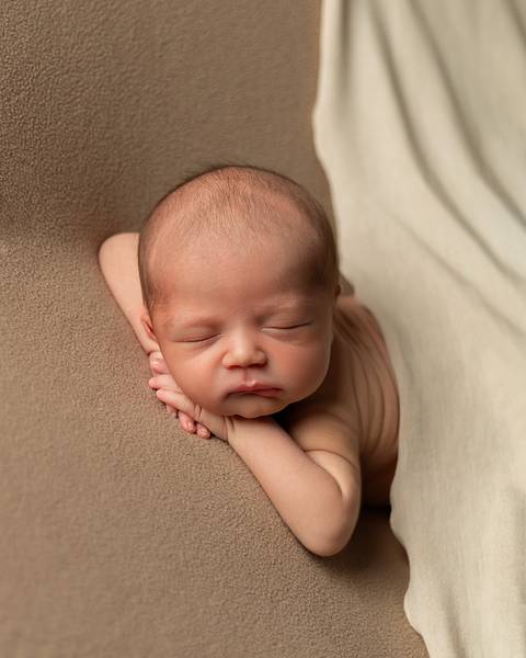 Ensaio Newborn em estúdio. Bebê recém-nascido dormindo em poof. '