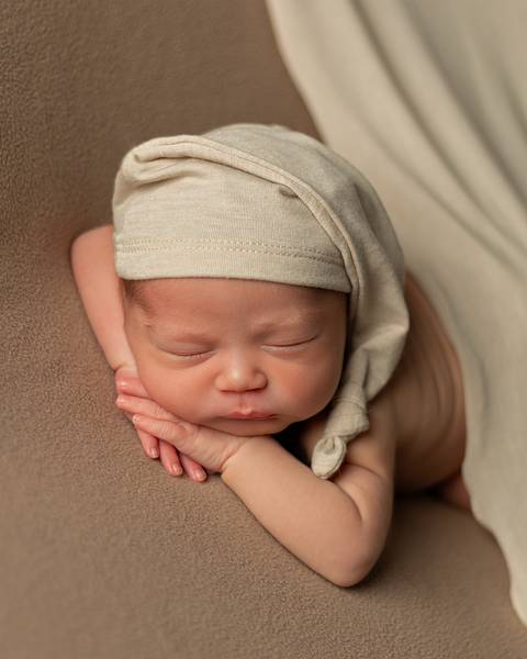 Ensaio Newborn em estúdio. Bebê recém-nascido dormindo em poof. '