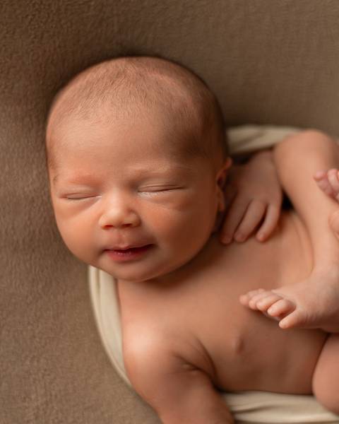 Ensaio Newborn em estúdio. Bebê recém-nascido dormindo em poof. '