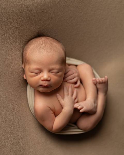 Ensaio Newborn em estúdio. Bebê recém-nascido dormindo em poof. '