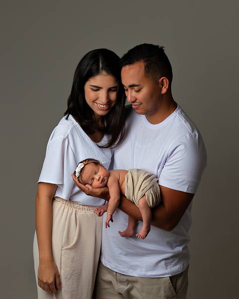 Bebê dormindo nos braços do pai, com a mãe ao lado, em ensaio Newborn em Natal/RN'