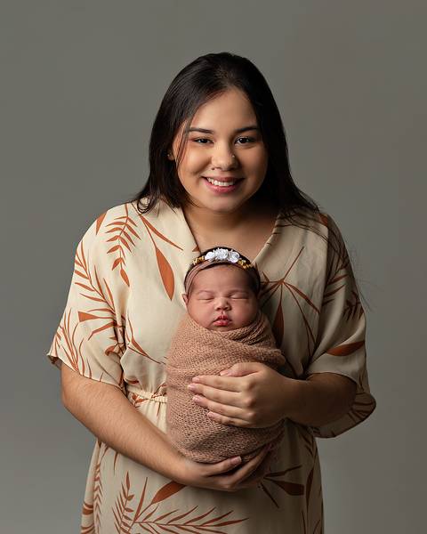 Bebê dormindo nos braços da mãe em ensaio newborn'