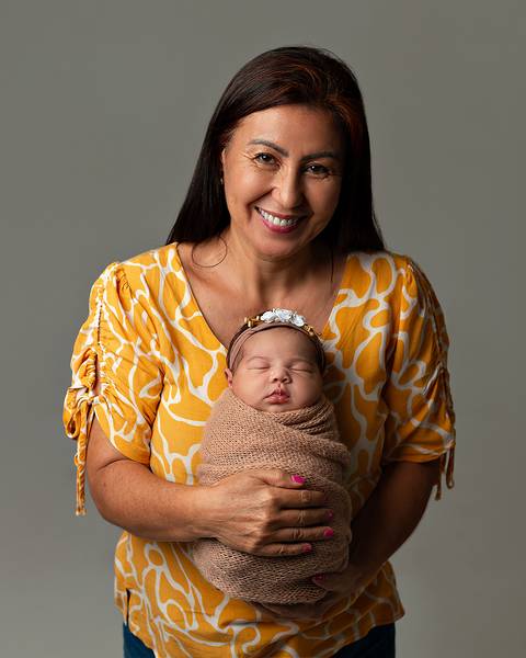 Bebê dormindo nos braços da avó em ensaio newborn'