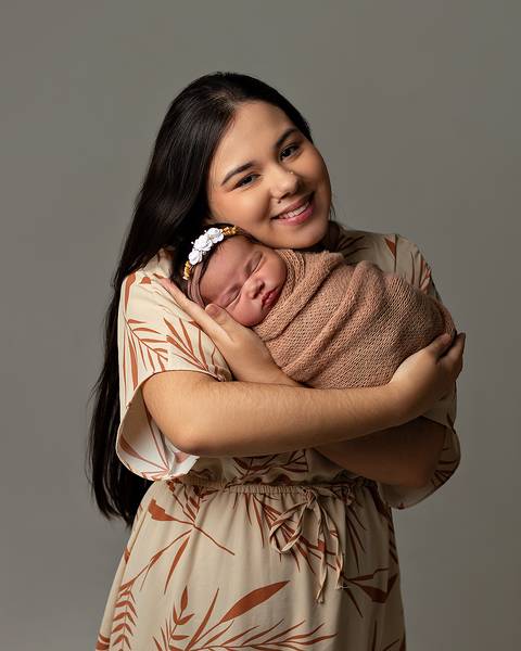 Bebê dormindo nos braços da mãe em ensaio newborn'