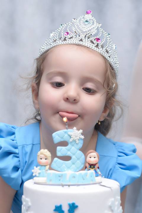 criança assoprando a velinha com a lingua de fora. cobertura fotografica infantil.  aniversario em salão de festas, fotografa aniversario no tatuape'