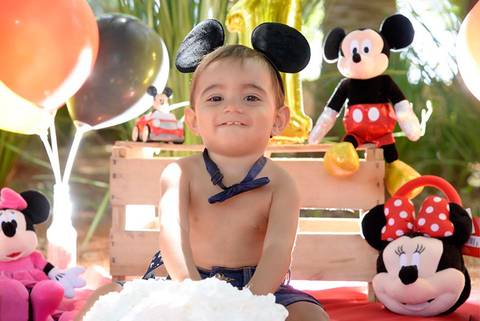 bebe sorrindo colocando a mao no bolo, Smash the cake tema mickey no parque, decoraçao com as cores do tema, fotografa smash no tatuape'