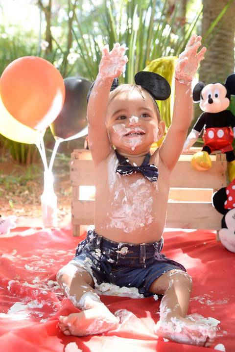 criança feliz no ensaio de um ano, sujo de bolo, Smash the cake tema mickey no parque, decoraçao com as cores do tema, fotografa smash infantil mooca tatuape e regiao'