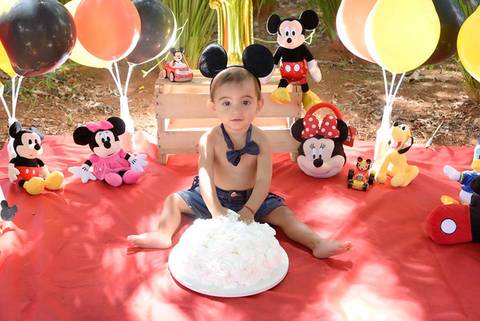 bebe colocando a mao no bolo no ensaio Smash the cake tema mickey no parque, decoraçao com as cores do tema, fotografa smahs e infantil no tatuape'