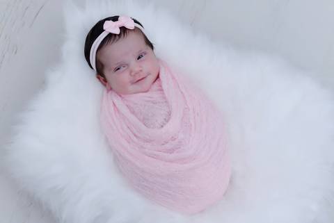 Bebe enrolado no wrap sorrindo, de lacinho e olhos abertos, ensaio newborn em casa, fotografa newborn e acompanhamento bebe no tatuape, newborn menina'