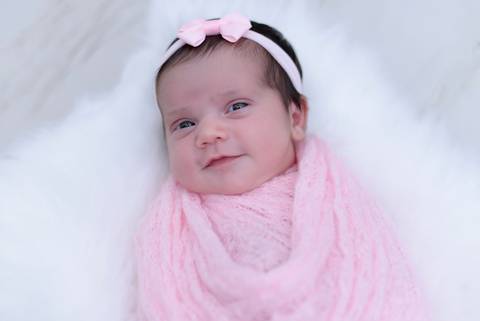 Bebe enrolado no wrap sorrindo, de lacinho e olhos abertos, ensaio newborn em casa, fotografa newborn e acompanhamento bebe no tatuape, newborn menina'